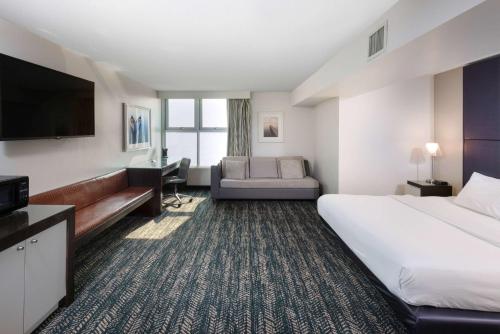 日内瓦41 Lakefront Hotel, Trademark Collection by Wyndham的酒店客房设有一张大床和一台电视。