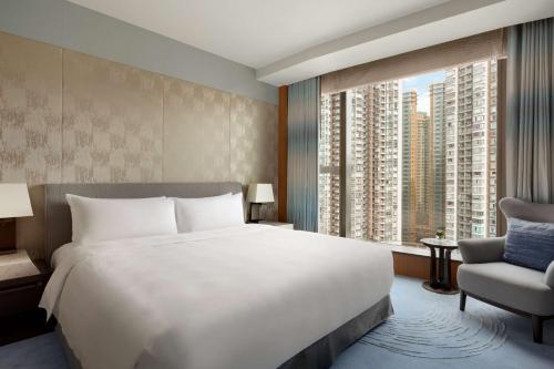 香港香港嘉里酒店的一间卧室设有一张大床、一把椅子和大窗户