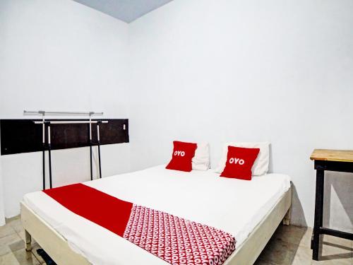 SunggalOYO 91959 La Khansa Homestay Syariah的一张带两个红色枕头的白色床