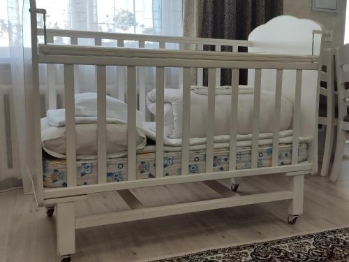 卡拉科尔Apartment in the Karakol heart的配有枕头和毯子的白色婴儿床