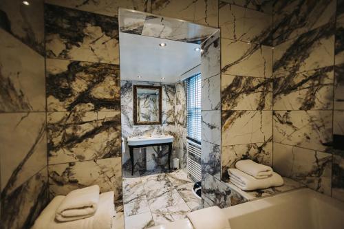 切尔德桑顿Brook Hall Hotel的浴室设有镜子、浴缸和水槽