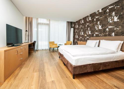 斯德勒基Tailormade Hotel SIHLPARK Schindellegi的配有一张床和一台平面电视的酒店客房