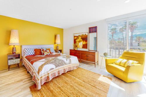 棕榈泉Upscale Uptown Permit# 5251的一间卧室配有一张大床和一张黄色椅子