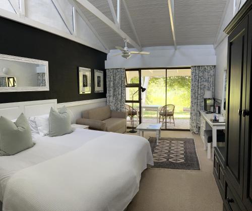 普利登堡湾Bitou River Lodge的一间带白色大床的卧室和一间客厅