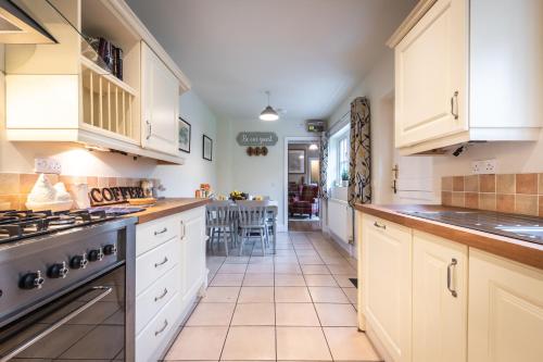 南安普敦Rustic cabin located in a serene forest setting的厨房配有白色橱柜和炉灶烤箱。