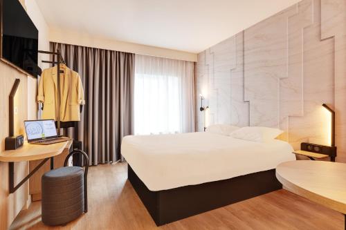 里尔B&B HOTEL Lille Lillenium Eurasanté的一间酒店客房,配有一张白色的床和一张书桌
