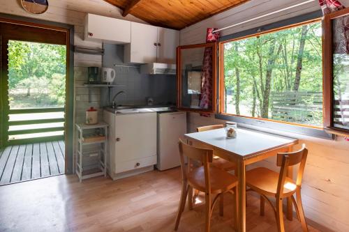 Bretagne-dʼArmagnacCamping les Lacs d'Armagnac的小屋内的厨房配有桌椅