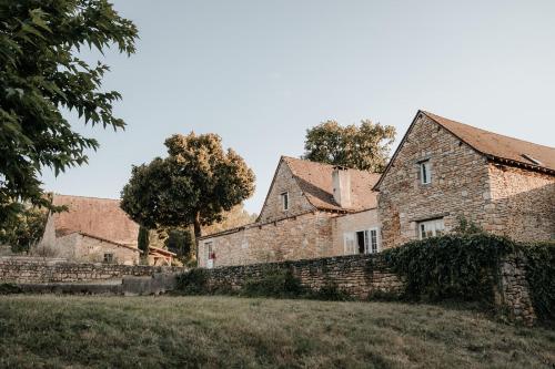 Saint-Amand-de-ColyDomaine St-Amand的一座古老的石头房子,有墙和树木