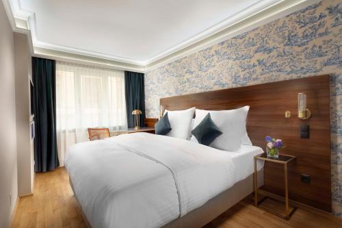 维也纳ARTIST Boutique Hotel的卧室配有白色大床和蓝色壁纸