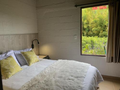 瓜塔佩Ecolodge Bahia del Peñón的卧室配有白色的床和窗户