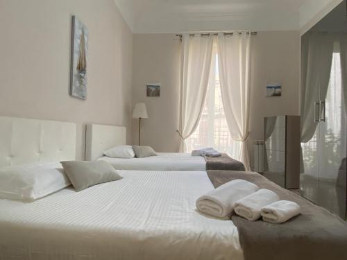 巴勒莫A casa da Carlo的白色客房内的两张床和毛巾