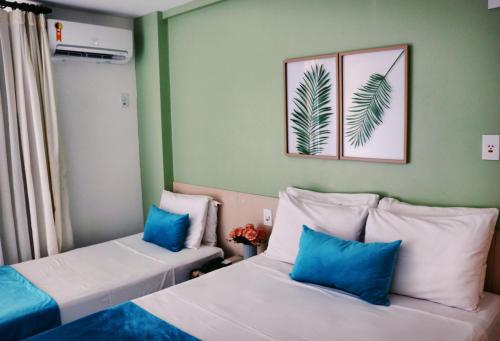 巴雷里尼亚斯Grand Lençóis Flat的配有绿色墙壁和蓝色枕头的客房内的两张床