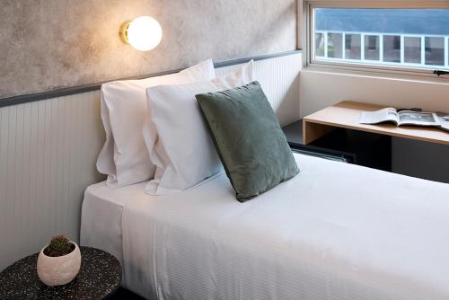 卧龙岗Hotel TOTTO Wollongong的卧室配有带白色枕头的床和窗户。