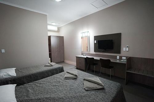 滕南特克里克Bluestone Motor Inn的酒店客房设有两张床和一台平面电视。