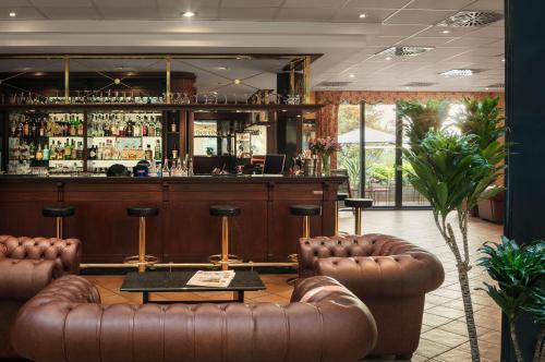 布拉格布拉格罗马酒店的一间酒吧,配有棕色皮革家具和吧台