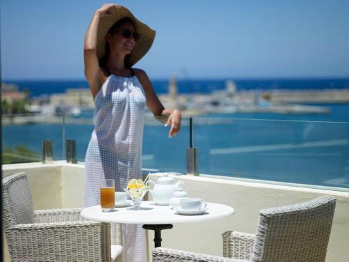 罗希姆诺基马海滩酒店的戴帽子的女人站在带桌子的阳台