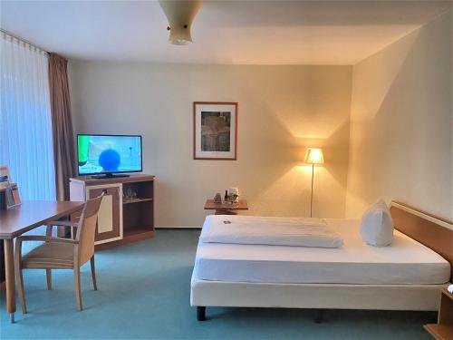 不莱梅Grothenns Hotel 3-Sterne superior的酒店客房配有一张床、一张书桌和一台电视。