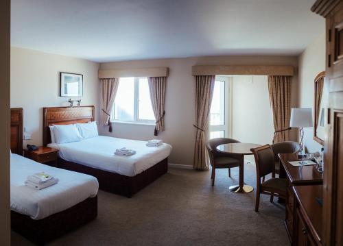 拉辛赫勒尔汉奇酒店的酒店客房带两张床和一张桌子以及椅子。