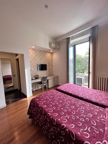 米兰阿斯普罗蒙特酒店的一间卧室配有一张大床和粉红色的床罩