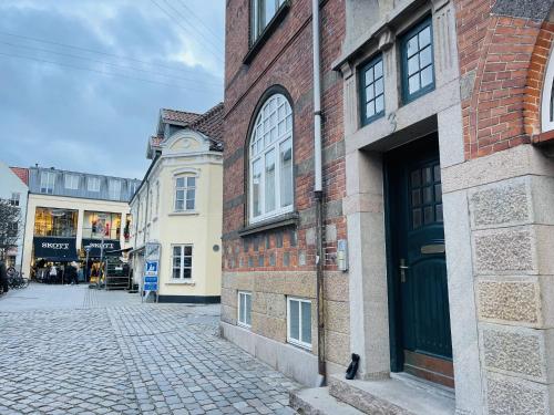奥尔堡aday - Luxurious Studio Apartment in the Heart of Aalborg的一条石铺街道,旁边是一座砖砌建筑