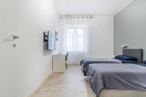 米兰Casaballi Milano MM3 Trilocale的配有白色墙壁和木地板的客房内的两张床