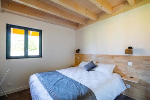 托农莱班Les Cottages de Ripaille的一间带一张大床的卧室,位于一个拥有木制天花板的房间