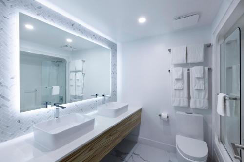 金斯顿Strata Hotel的白色的浴室设有两个盥洗盆和镜子