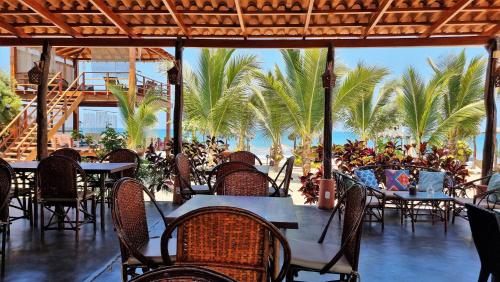卡诺阿斯德蓬萨尔Punta del Norte Bungalows的一间设有桌椅的餐厅,种植了棕榈树