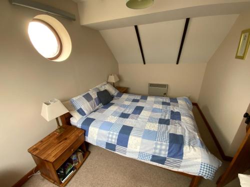 切尔滕纳姆Sherbourne Cottage, Seven Springs Cottages的卧室配有蓝色和白色的床和窗户。