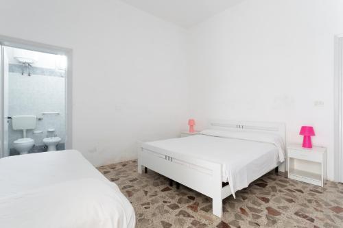 托雷莫泽Appartamento fronte mare e spiaggia的一间白色卧室,配有两张床和镜子