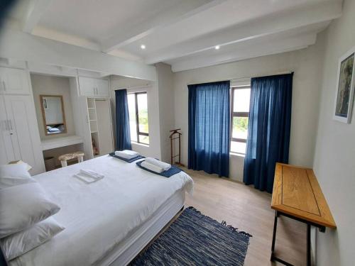 阿尔弗雷德港Angel's Rest的卧室配有一张带蓝色窗帘的大型白色床