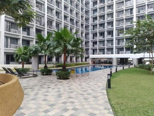 马尼拉Your home in the city的一座大型公寓楼,设有游泳池和棕榈树