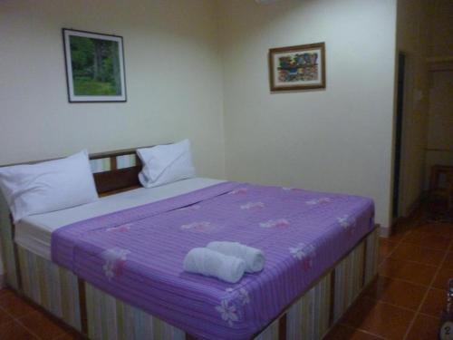 甘烹碧班定巴拉米度假酒店的一间卧室配有一张紫色床和毛巾
