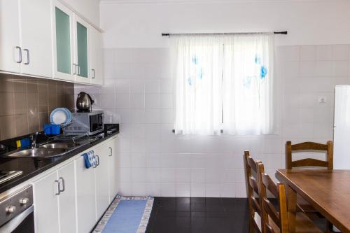 蓬他达维托亚Casa do Sol的厨房配有白色橱柜、桌子和窗户。