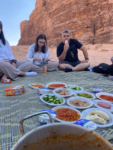 瓦迪拉姆wadi rum land mars的一群坐在海滩上吃食物的人