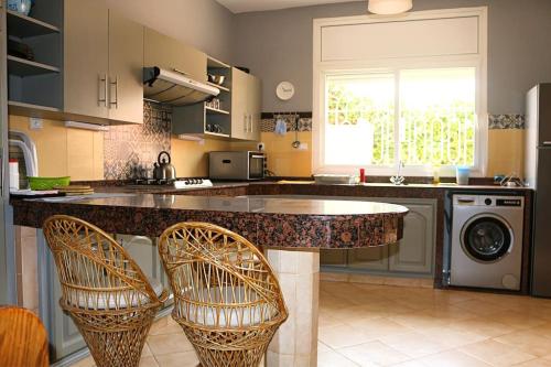 伊米乌阿达尔Villa spacieuse avec places de Parking gratuites的厨房配有带2把椅子的柜台和洗碗机。