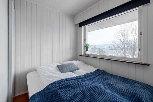 特罗姆瑟Modern apartment in the center of the island的一间卧室配有一张带蓝色毯子的床和窗户。