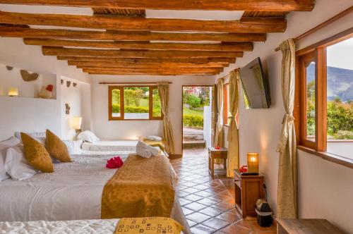 莱瓦镇Casa de Campo Hotel & Spa的一间卧室设有两张床、一台电视和窗户。