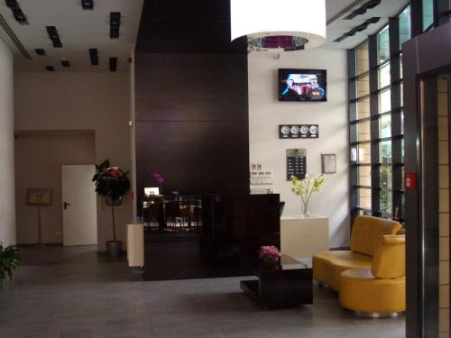 布加勒斯特贝特洛酒店的大堂设有黄色椅子和墙上的电视