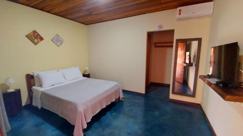 戈亚斯州上帕莱索Chalés Flor de Manacá的卧室配有白色的床和电视。
