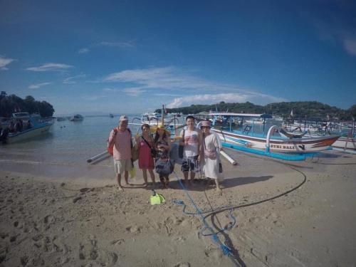 八丹拜SNORKELING AT PADANGBAI BY KAI TRIP TOMORROW的一群人站在海滩上,坐船