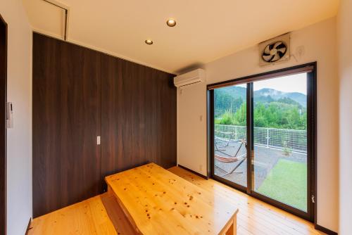 Aki日本の秘境で味わう絶品地鶏 ジローのおうち的客房铺有木地板,设有大窗户。