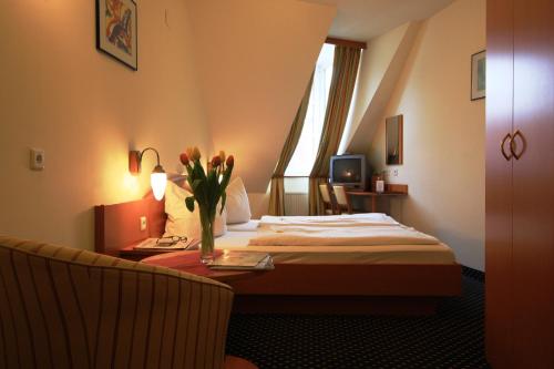 维也纳祖尔欧泊900米套房酒店的一间酒店客房,配有一张床和一张桌子上的花瓶