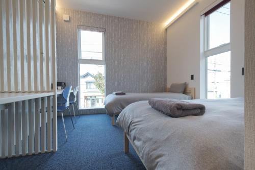 俱知安町Tbox的一间卧室设有两张床和两个窗户。