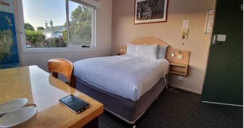 德文港The Dannebrog Lodge的配有一张床、一张桌子和一张桌子的酒店客房