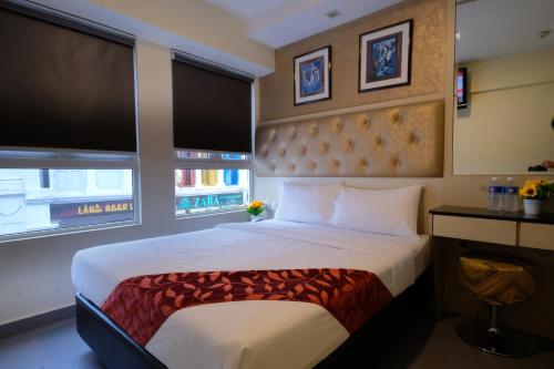 新加坡Sandpiper Hotel Singapore的一间卧室设有一张大床和两个窗户。