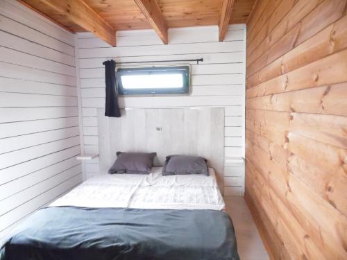 杜埃拉丰坦Chalet cosy climatisé avec parking et Internet的一间小卧室,配有一张木墙床