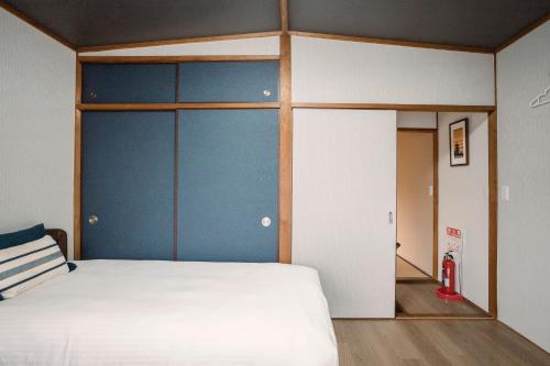 京都Tofukuji Saku Inn（东福寺咲く宿）的卧室配有白色的床和蓝色的墙壁