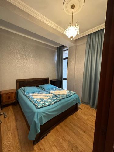 第比利斯Sun Apartment的一间卧室配有一张带蓝色床单和吊灯的床。