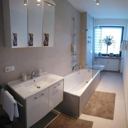 格门德蒂格斯Wohnung direkt am Tegernsee mit XL-Terrasse的浴室配有2个盥洗盆、浴缸和淋浴。